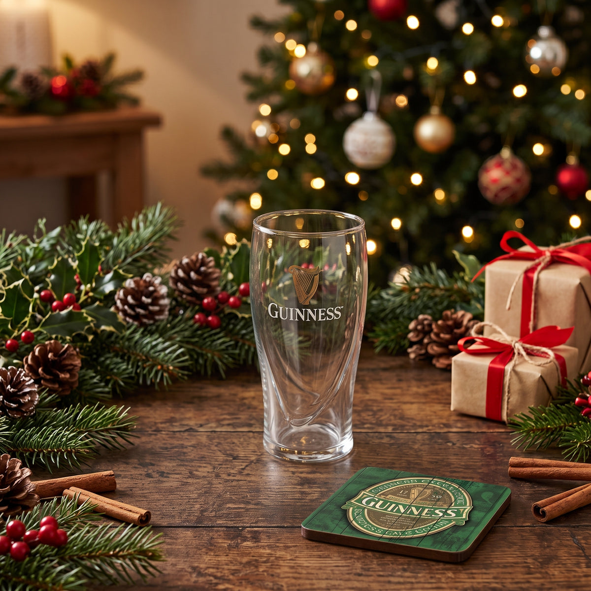 A The Little Guinness Gift glass and square coaster on a wooden table surrounded by Christmas decorations.