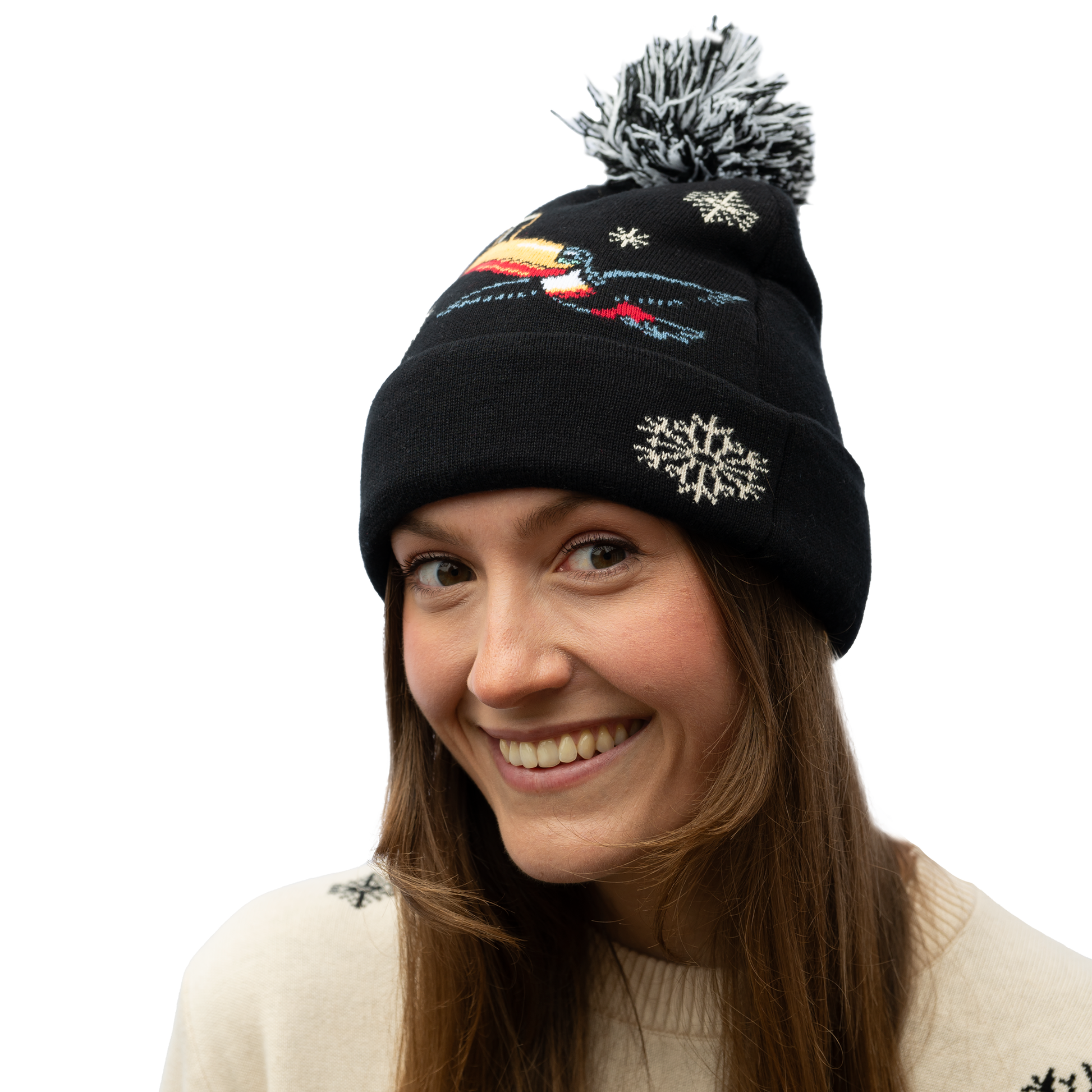 A person wearing a Guinness Holiday Toucan Beanie from the Guinness Webstore US, featuring snowflake and bird designs, is smiling against a white background, adding a touch of charm to their winter wardrobe.