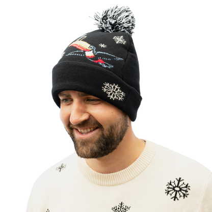 A man adds a touch of festive cheer to his winter wardrobe by wearing the Guinness Holiday Toucan Beanie from Guinness Webstore US, a black knit hat adorned with a snowflake pattern and a playful pom-pom. He pairs this striking accessory with a cream-colored sweater featuring matching snowflakes.