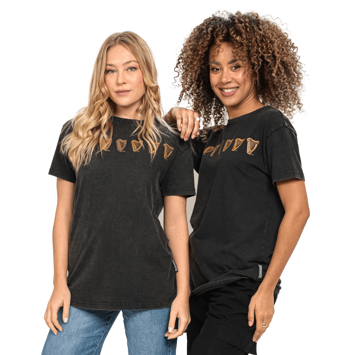 Two women standing next to each other wearing black Guinness Evolution Harp Tees.