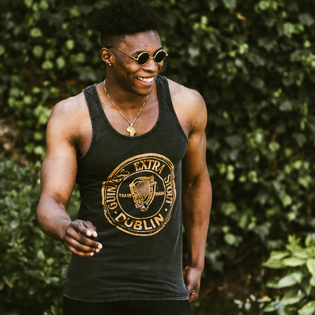A young man wearing Guinness Washed Extra Stout Tank Top and sunglasses enjoying the summer months.