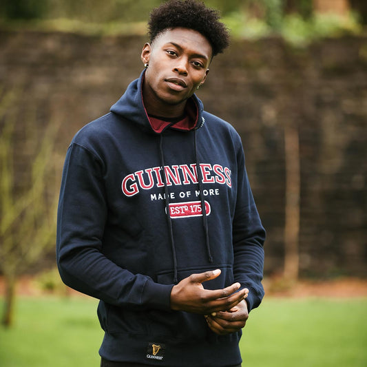 A young man wearing an embroidered Guinness Signature Navy Hooded Sweatshirt.