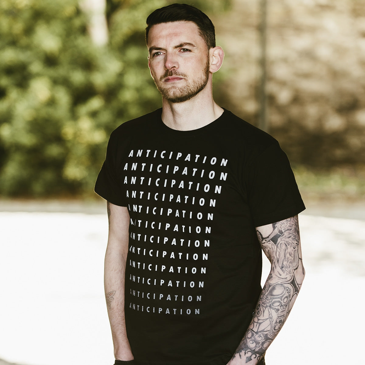A man with tattoos wearing a Guinness Anticipation Pint Tee, showcasing both comfort and style.