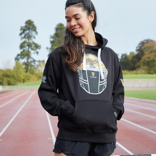 A woman celebrating in a Guinness Notre Dame Helmet Hoodie Black, representing comfort.