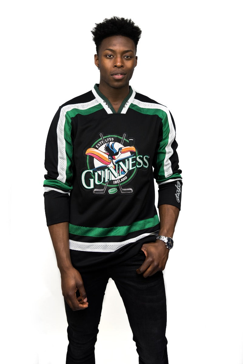 A man wearing a Guinness Toucan Hockey Jersey Black and Green.