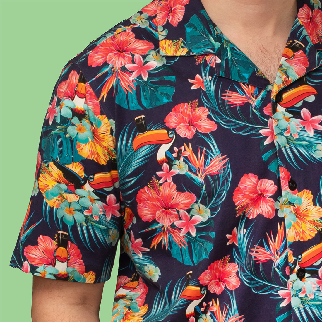 A man sporting a vibrant Guinness Toucan Hawaiian shirt with tropical plants and flowers.