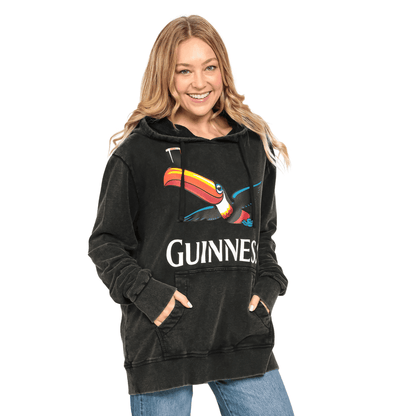 A woman wearing a black Guinness Premium Label Toucan Hoodie featuring the iconic toucan.