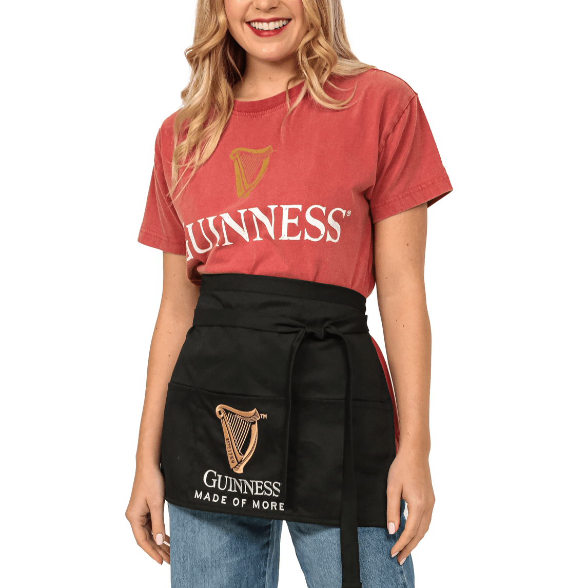 A woman wearing a Guinness apron while enjoying a cup of Guinness Kitchen Gift Box Ground Coffee.