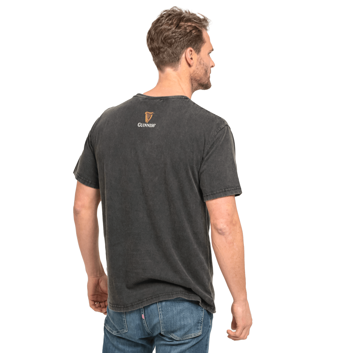 The back of a man wearing jeans and a t-shirt with a Guinness Evolution Harp Tee logo.