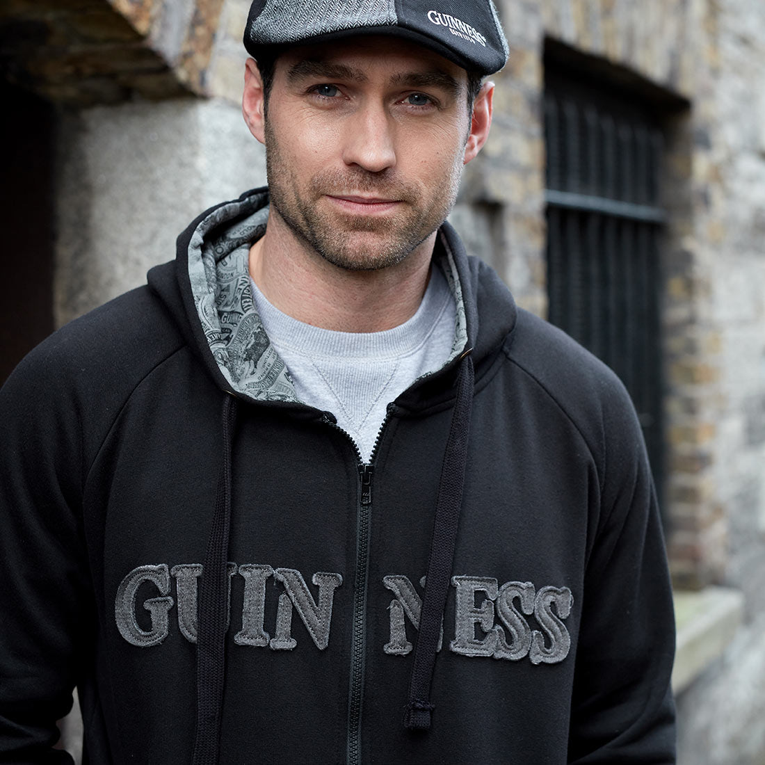 A man wearing a Guinness Vintage Black & Grey Label Lined Hoodie.