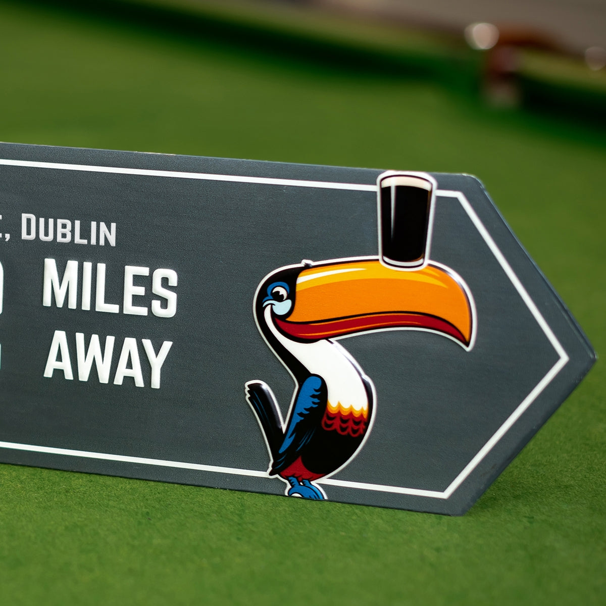 A Guinness Open Gate Brewery Arrow Metal Sign featuring a toucan with a hat on it, promoting Guinness and the Open Gate Brewery.