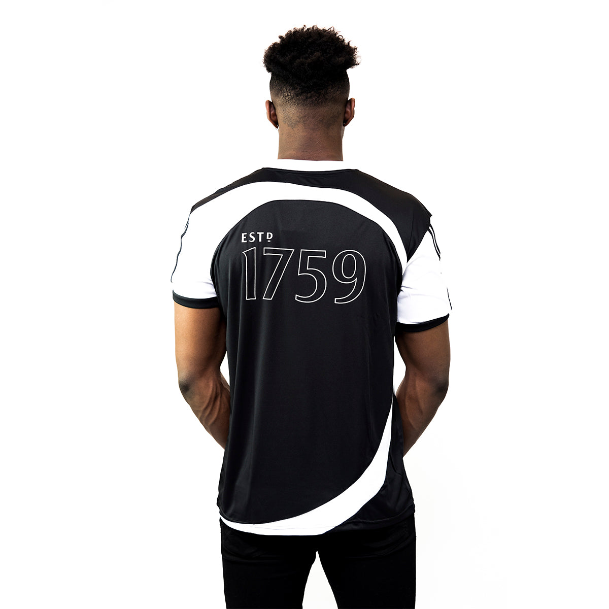 A person wearing a Guinness Black & White Soccer Jersey, featuring "ESTD 1759" on the back, stands against a plain white background.