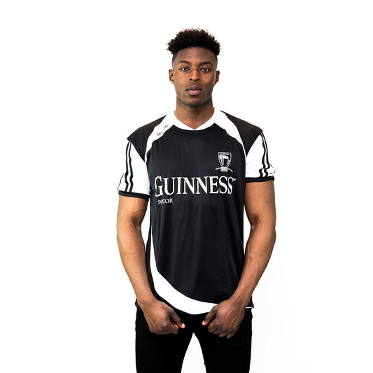 A proud soccer fan stands before a white backdrop wearing the timeless Guinness Black & White Soccer Jersey from the Guinness Webstore US, subtly adorned with the iconic "1759" number.