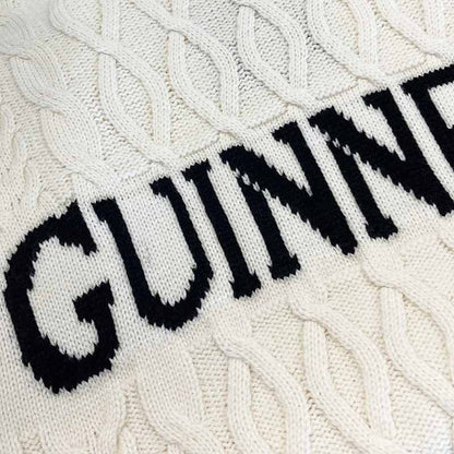 Close-up of the Guinness Cream Cable Knit Jumper by Guinness Webstore US, showcasing classic Aran cable patterns and bold black "GUINNESS" lettering—a must-have winter essential.
