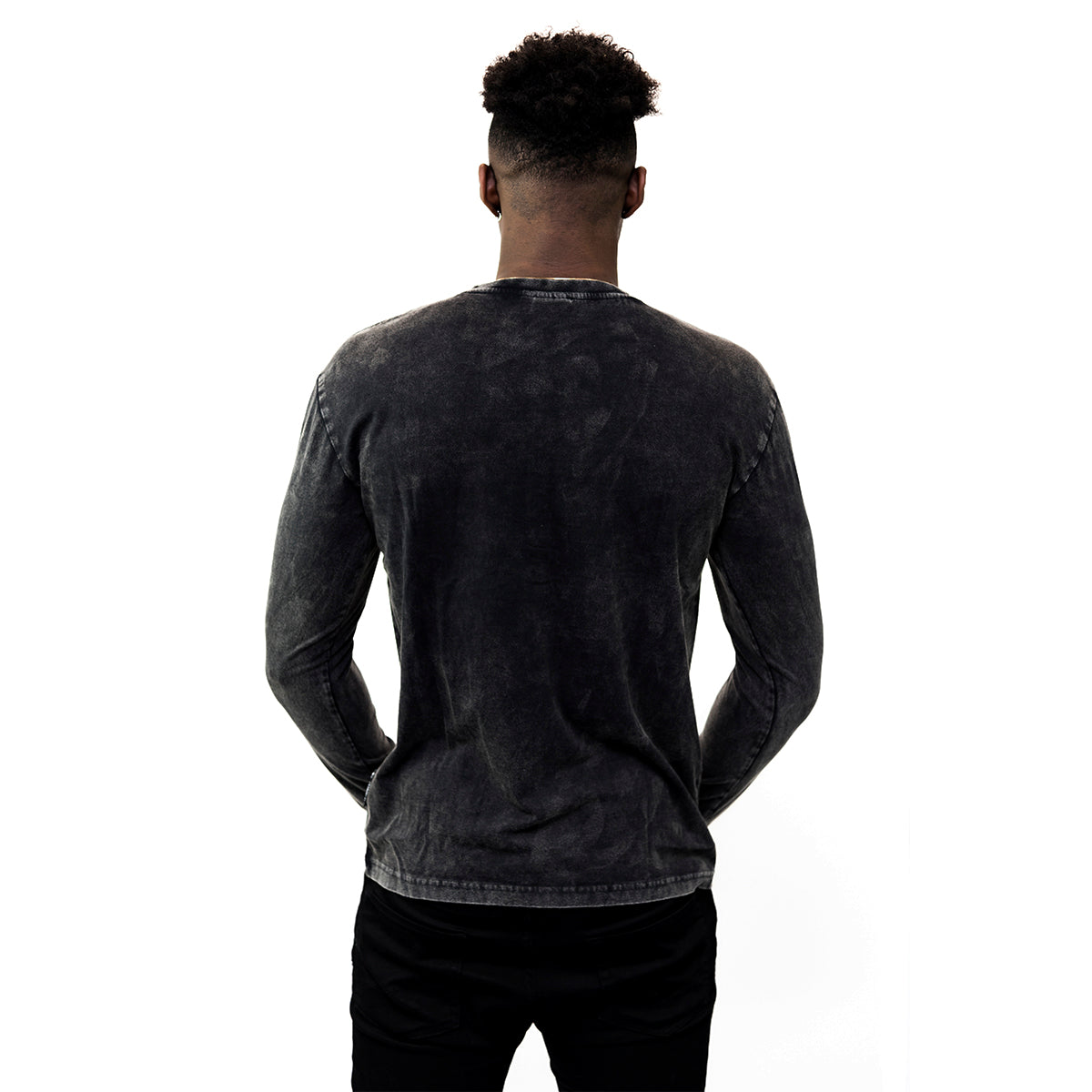 Someone stands with their back to the camera against a white background, wearing black pants and a long-sleeve Guinness Classic Washed Black Henley, made from premium combed cotton.