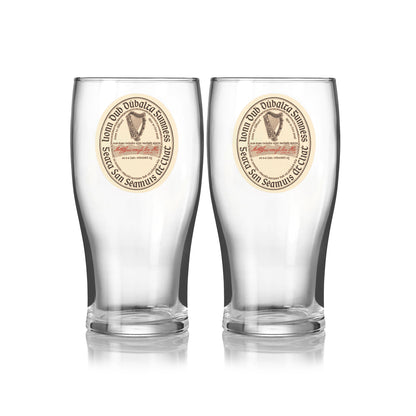The Guinness Webstore US Guinness Vintage Label Pint Glass - 2 Pack includes two clear pint glasses with matching round vintage label designs, featuring “St. James’s Gate Dublin Extra Stout,” text, and an illustration on the front.