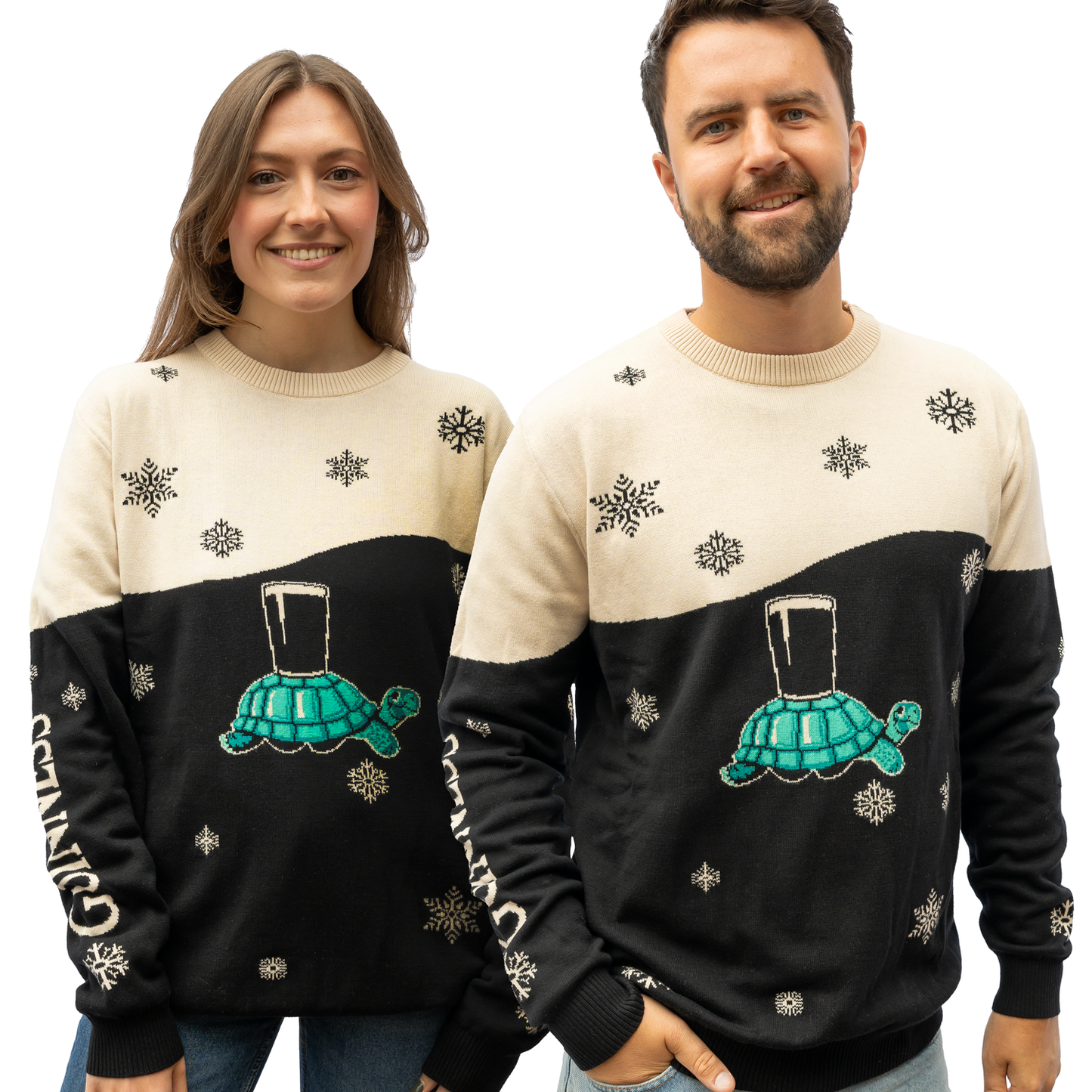 Two individuals are wearing coordinated sweaters from the Guinness Webstore US collection, featuring a black and cream design embellished with snowflakes, a playful tortoise print, and a pint glass motif.